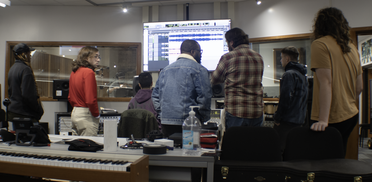 MATC+students+gather+around+the+audio+board+to+watch+a+recording+session+in+instructor+Matt+Smiths+class.+He+is+having+a+student+%E2%80%98tweak+the+EQ%E2%80%99+on+the+track%2C+which+adjusts+the+frequency+levels+on+the+equalizer.+